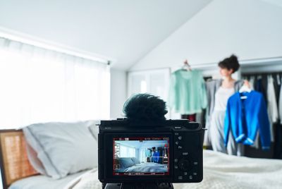 Image of a camera set on a tripod, shooting a woman