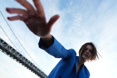 Wide-angle portrait of woman with part of suspension bridge span in background