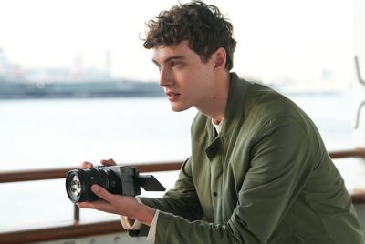 رجل يلتقط الصور أثناء المشي على سطح قارب مع كاميرا محمولة باليد، يستخدم شاشة LCD للمراقبة