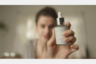 Image of a woman holding a makeup item in her hand, reviewing it