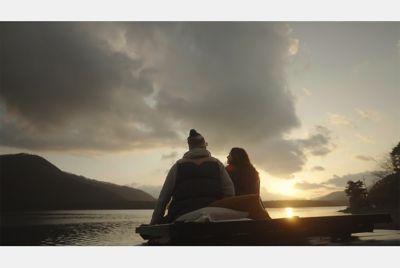 Image of two people sitting close to each other, with an evening scene in background