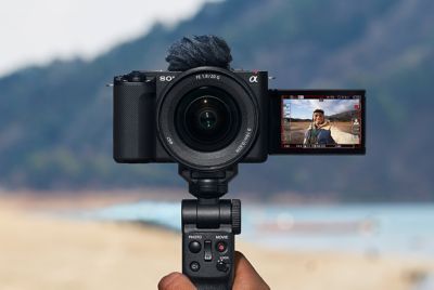 Image of a camera with hand grip attached and its flip screen open