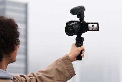 Image of a man holding a grip attached to a camera, taking a selfie