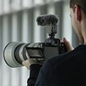 Image of a man shooting a movie with a woman as the subject of the shot