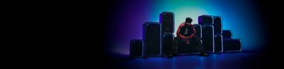 A dynamic wall of the ULT POWER SOUND speakers stacked in varying vertical and horizontal orientations, with each unit outlined by glowing, neon blue LED light rings against a blue and teal gradient background. A person wearing a dark jacket with orange stripes and sunglasses sits on the ULT TOWER MAX speaker in the middle.