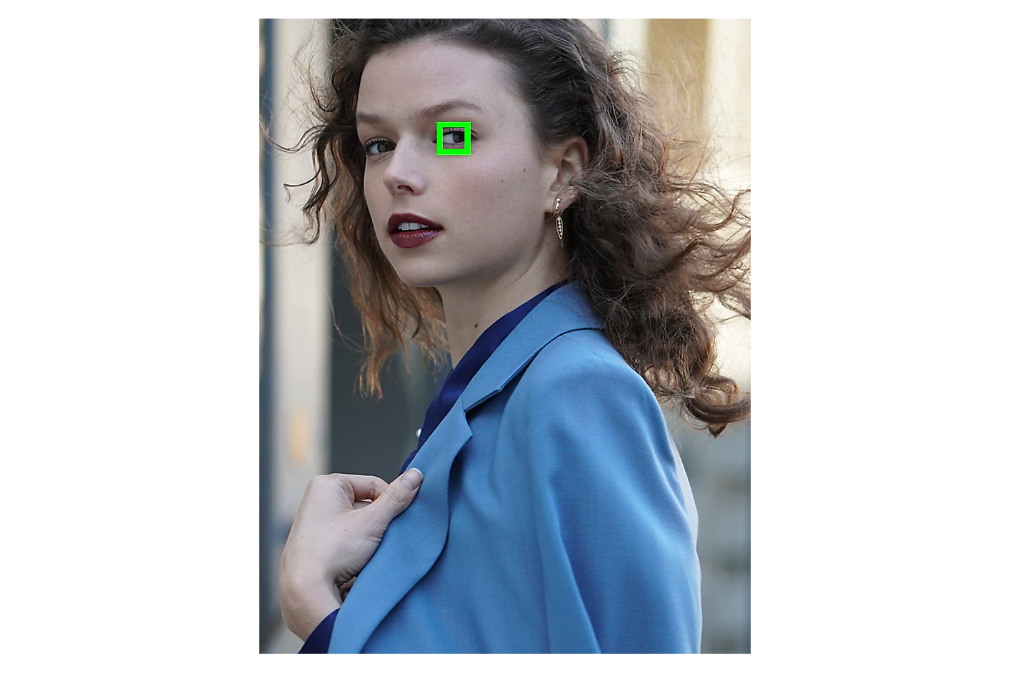 푸른색 재킷을 입고 측면을 바라보는 여성의 한쪽 눈에 잡힌 녹색 프레임.