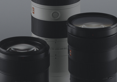 Three black and white Sony Alpha lenses on a grey background