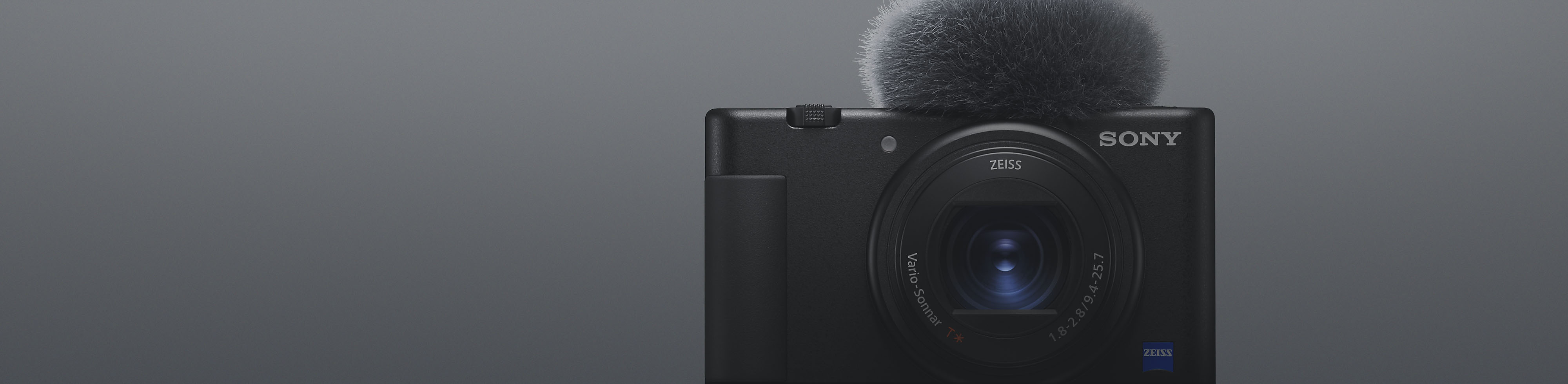 Pogled od spredaj na črno kompaktno kamero Sony s priključenim mikrofonom