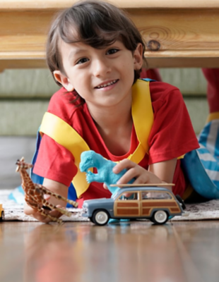 Un garçon portant un t-shirt rouge joue avec des jouets sur le sol