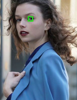 A woman in a blue jacket looks to the side with a green square framing one eye.