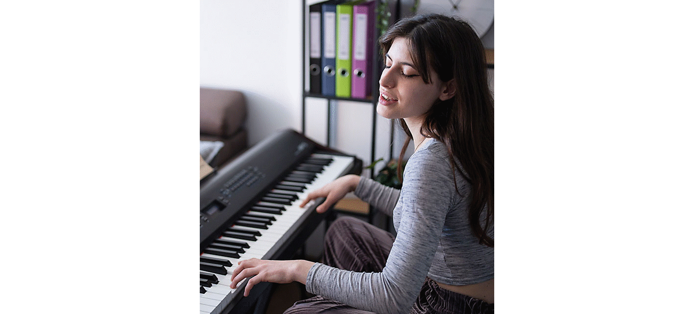 圖中的女子坐在起居室裡邊彈電子琴邊唱歌