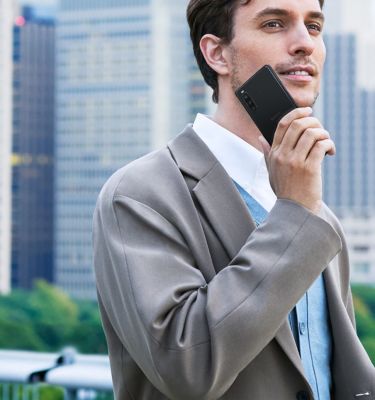 Un hombre con un traje gris sujeta un smartphone negro a la altura de la cara