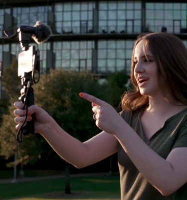 Женщина снимает себя на видео на смартфон Xperia, к которому прикреплена рукоятка