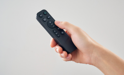Main tenant une télécommande BRAVIA avec des commandes intuitives pour le réglage du volume et du son.