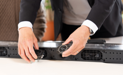 Close-up seseorang menunjukkan unit speaker dari soundbar.