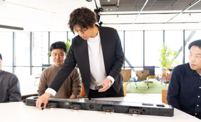 Insinyur memeragakan komponen internal soundbar selama diskusi.