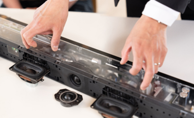 Close-up seseorang memegang komponen soundbar dalam peragaan.