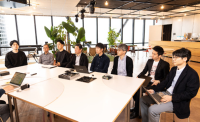 Група програмери од Sony седат на маса и дискутираат.