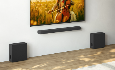 Σαλόνι με επιτοίχια τηλεόραση, soundbar και δύο subwoofer αριστερά και δεξιά της τηλεόρασης.