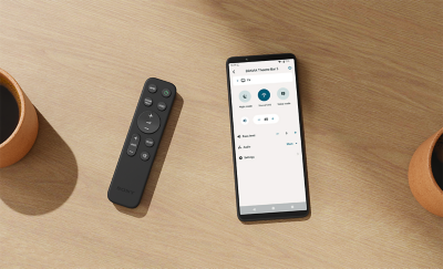 Sony hangprojektor távvezérlője egy okostelefon mellett, amelyen a BRAVIA Connect alkalmazás látható