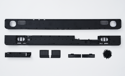 Image of a soundbar broken down into seven components next to a pile of plastic pellets.