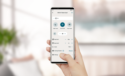 Hand holding a smartphone with BRAVIA Connect app on screen showing app control of BRAVIA Theatre Quad 