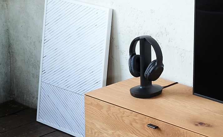 Lifestyle shot of in-home wireless headphones on a wooden console in a modern living room