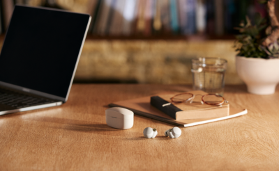Écouteurs sans fil blancs à côté de leur boîtier de charge sur une table en bois