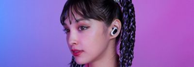 A gamer wearing the white INZONE Buds with a purple and pink background