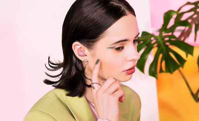 A stylish person wearing a pair of pink earbuds.