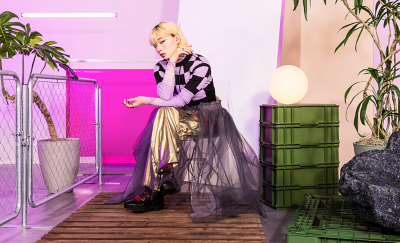 Một người sành điệu đang ngồi trong căn phòng màu hồng và đeo cặp tai nghe màu hồng.