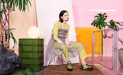 핑크색 이어버드 한 쌍을 착용하고 핑크색 방에 앉아 있는 스타일리시한 사람