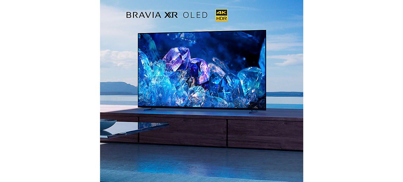 BRAVIA A80K trên tủ gỗ ở phòng khách với hình ảnh những viên pha lê màu xanh lam và tím trên màn hình