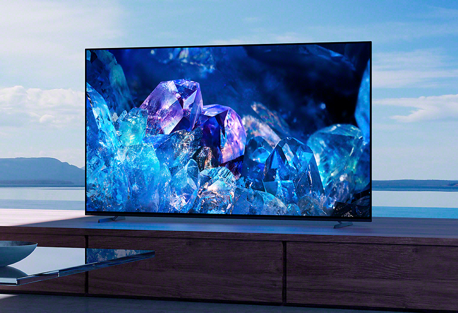 BRAVIA A80K on wooden cabinet in living room with image of blue and purple crystals on screen