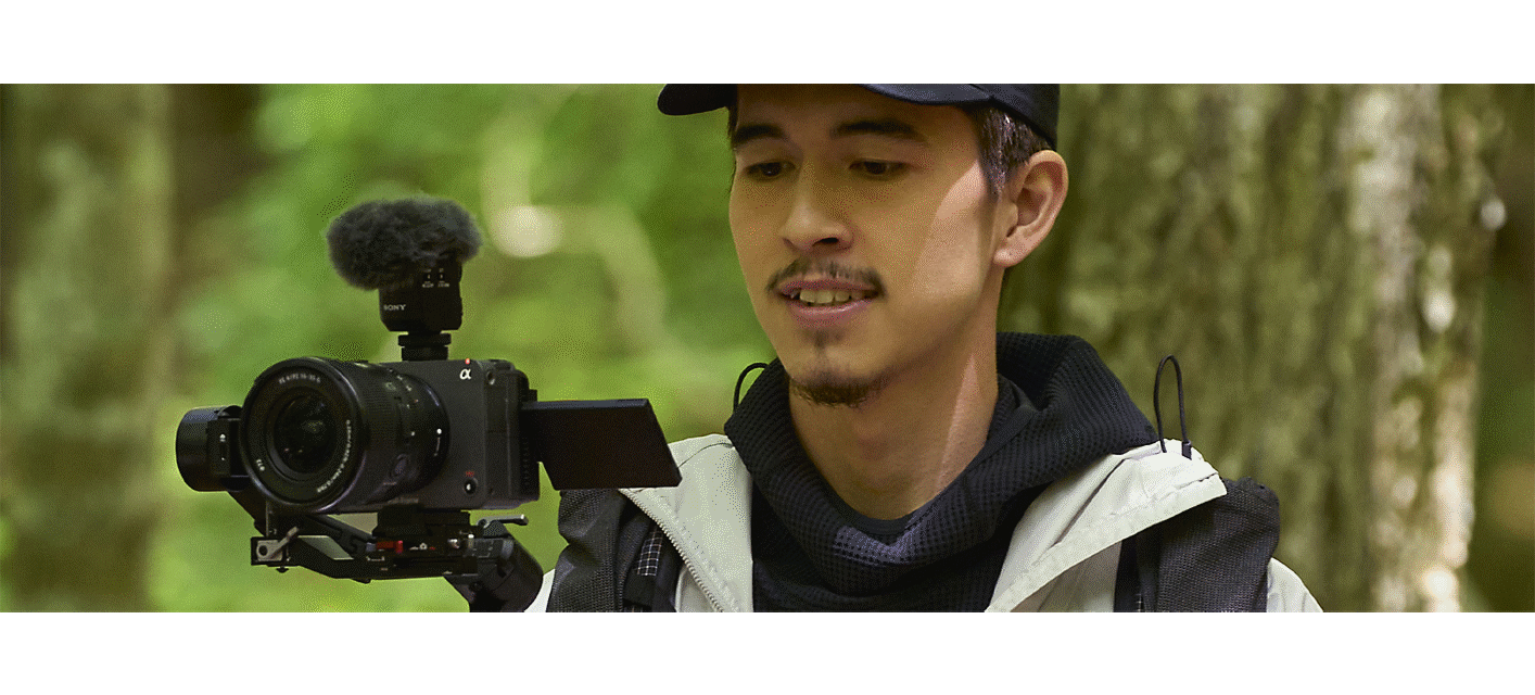 Usage image of a user shooting video with camera mounted on a gimbal, with microphone and wind screen attached