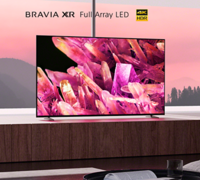 BRAVIA X90K on wooden platform in living room with image of pink crystals on screen