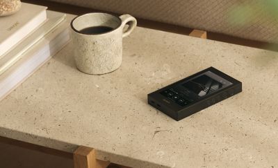 Sony NW‑ZX900 resting on a living‑room coffee table beside a mug and stacked books