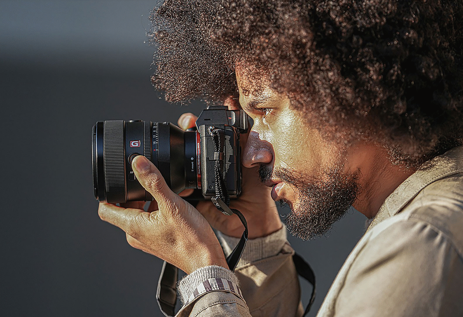 Obrázok osoby držiacej fotoaparát s pripevneným objektívom FE 50 mm F1,2 GM
