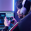 A pro gamer wearing a headset, playing on Xperia 1 IV Gaming Edition connected to two monitors