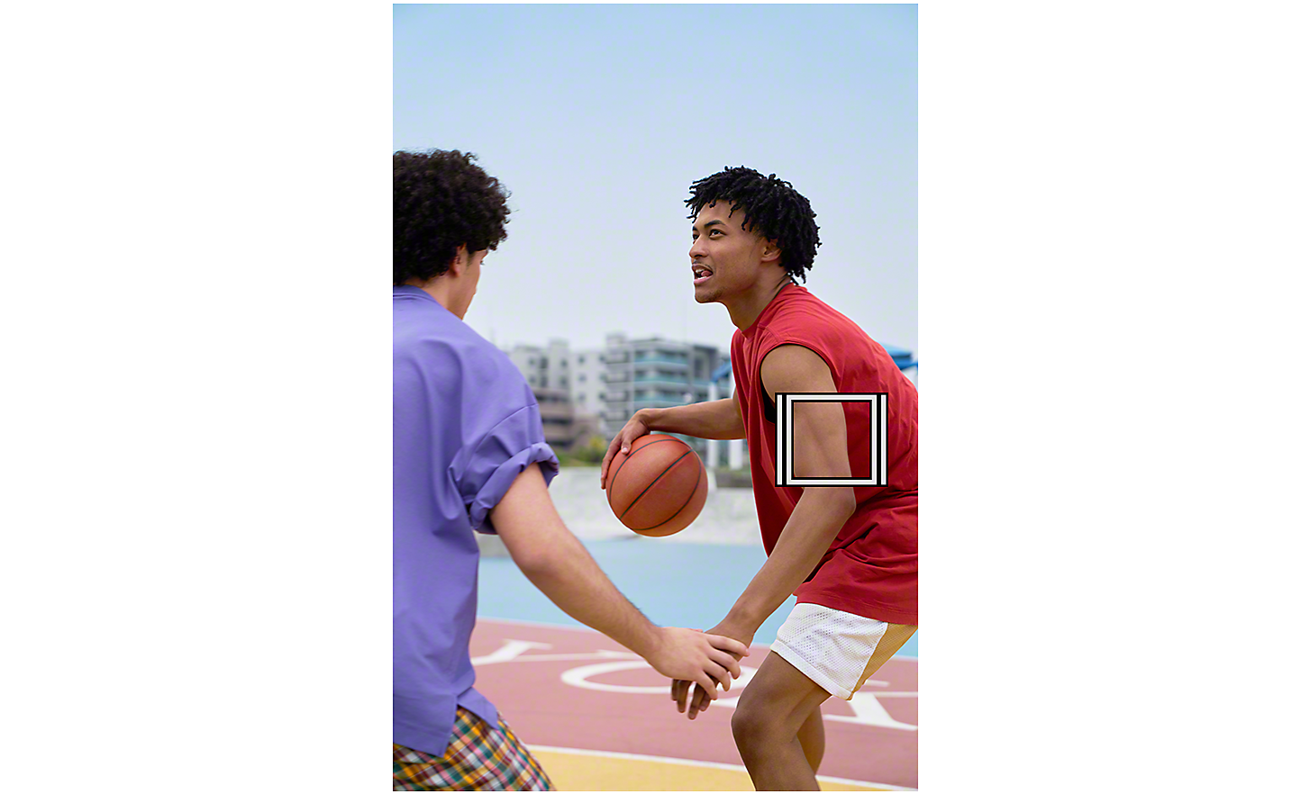 Deux hommes jouant au basket en extérieur, un carré blanc représentant le suivi d'objet