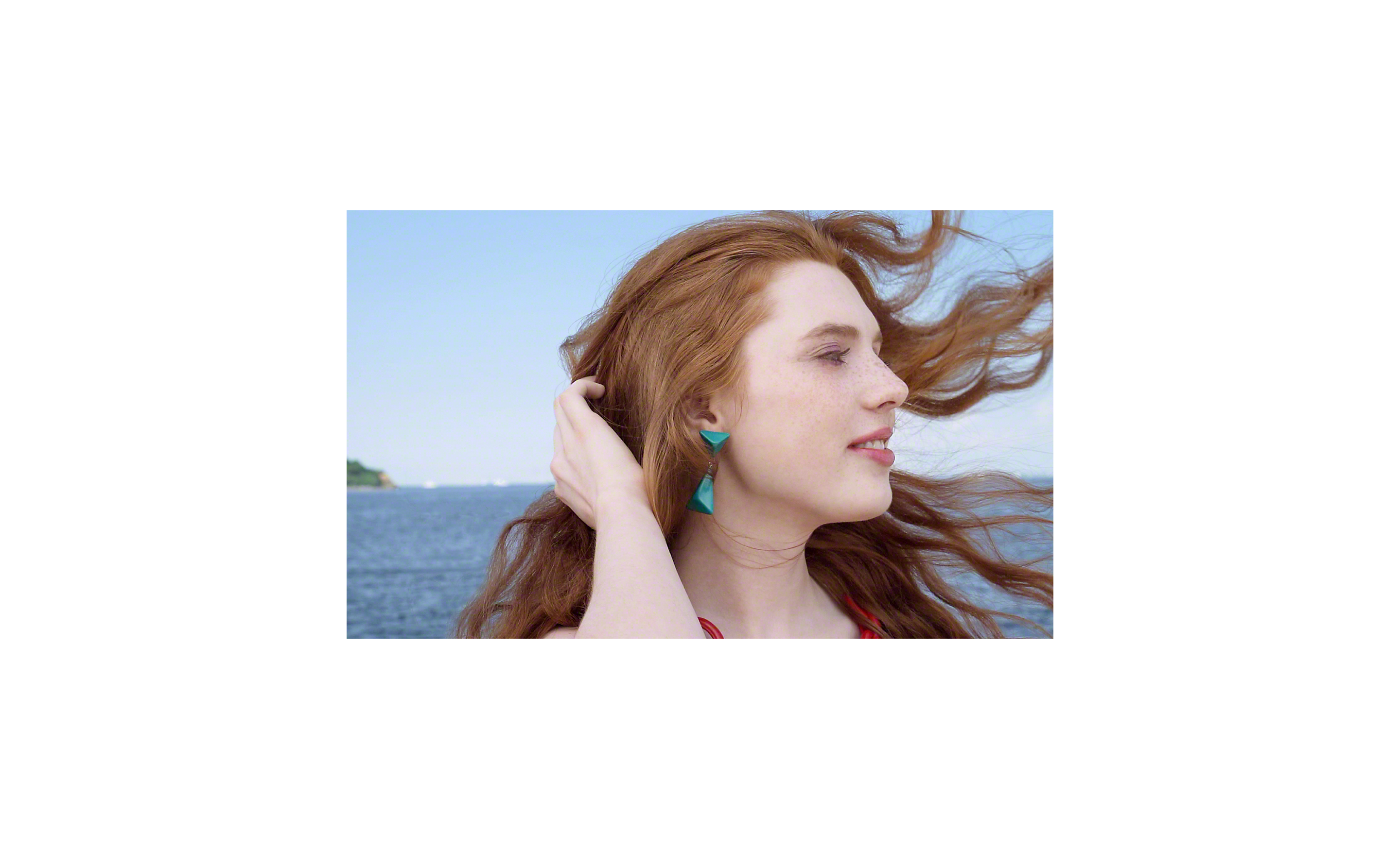 Nahaufnahme einer Frau, das Haar weht im Wind, das Meer im Hintergrund