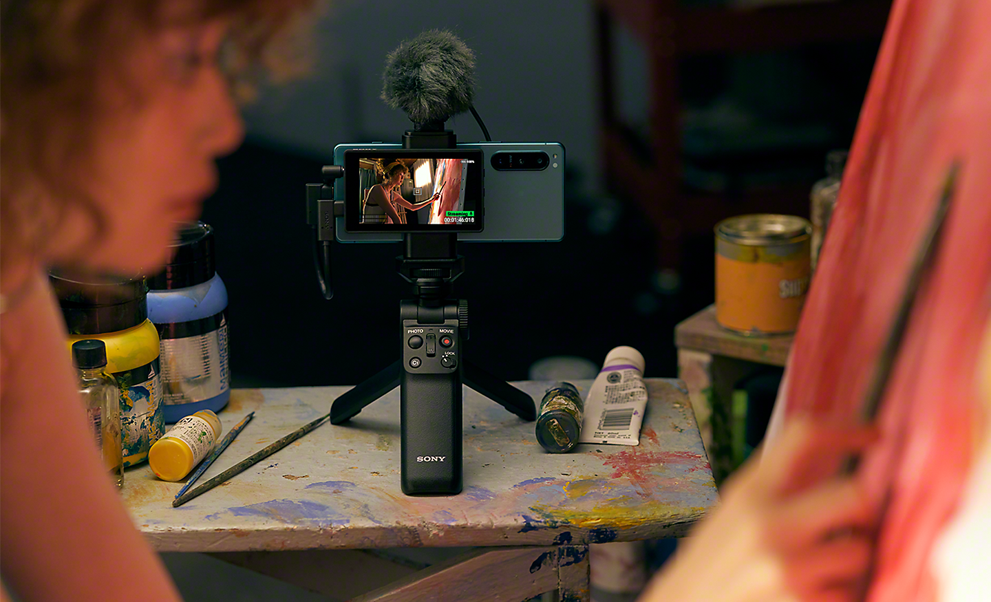 Eine Frau nimmt ein Selfie-Video mit dem Xperia 5 IV auf, mit externem Mikrofon, Mini-Stativ und Bluetooth-Aufnahmegriff
