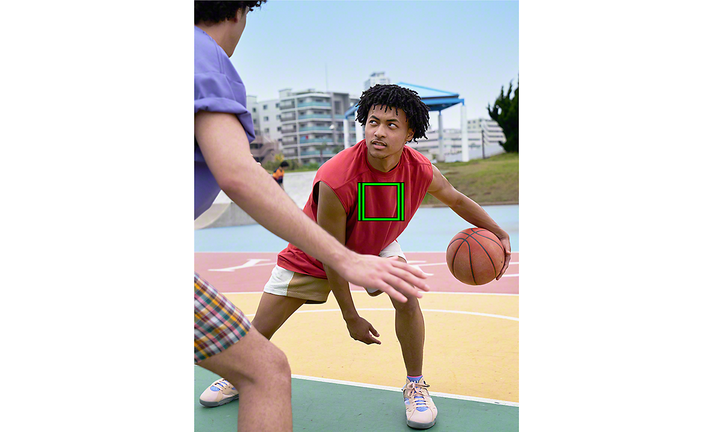 A basketball player eyeing his opponent, a green square on his body denoting Real-time Tracking