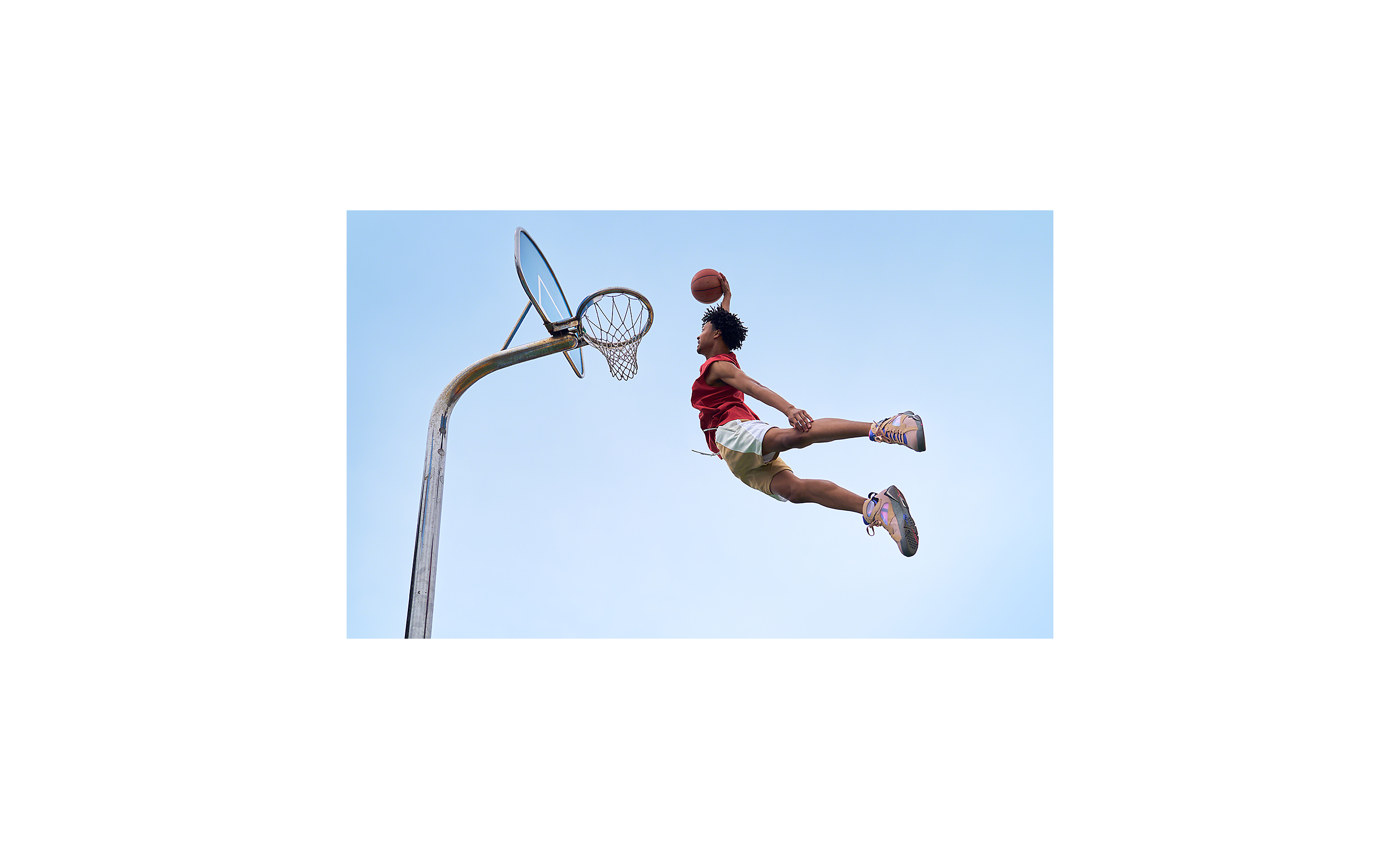 Opname van een basketbalspeler die midden in de lucht hangt en op het punt staat de bal met een dunk in de basket te slaan