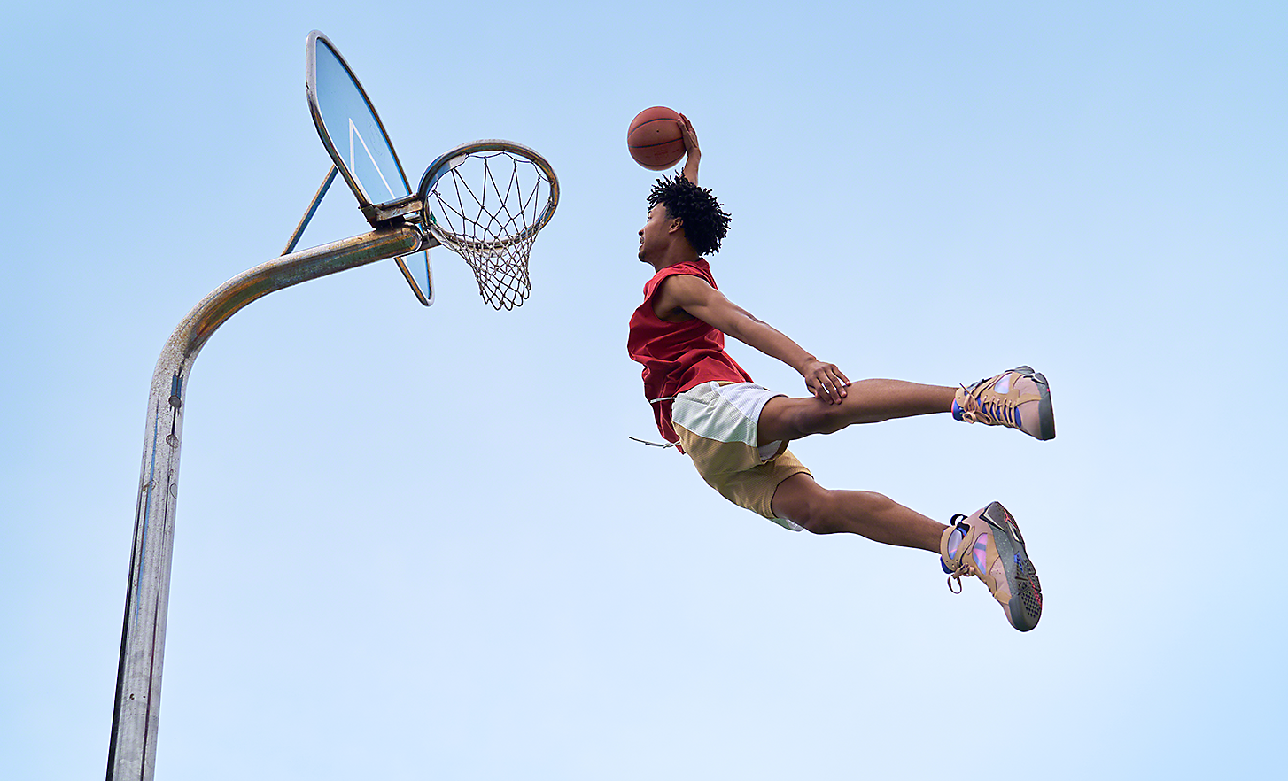 Dramatic shot of basketball player in mid-air about to slam dunk