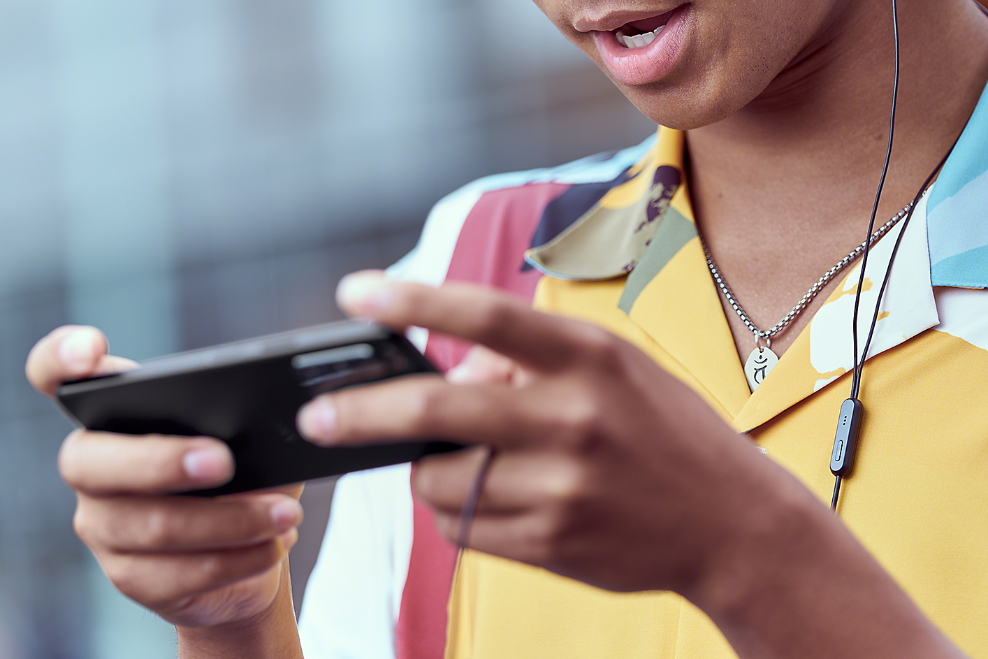 Záber z blízka na mladého muža, ktorý hrá na smartfóne Xperia 5 IV