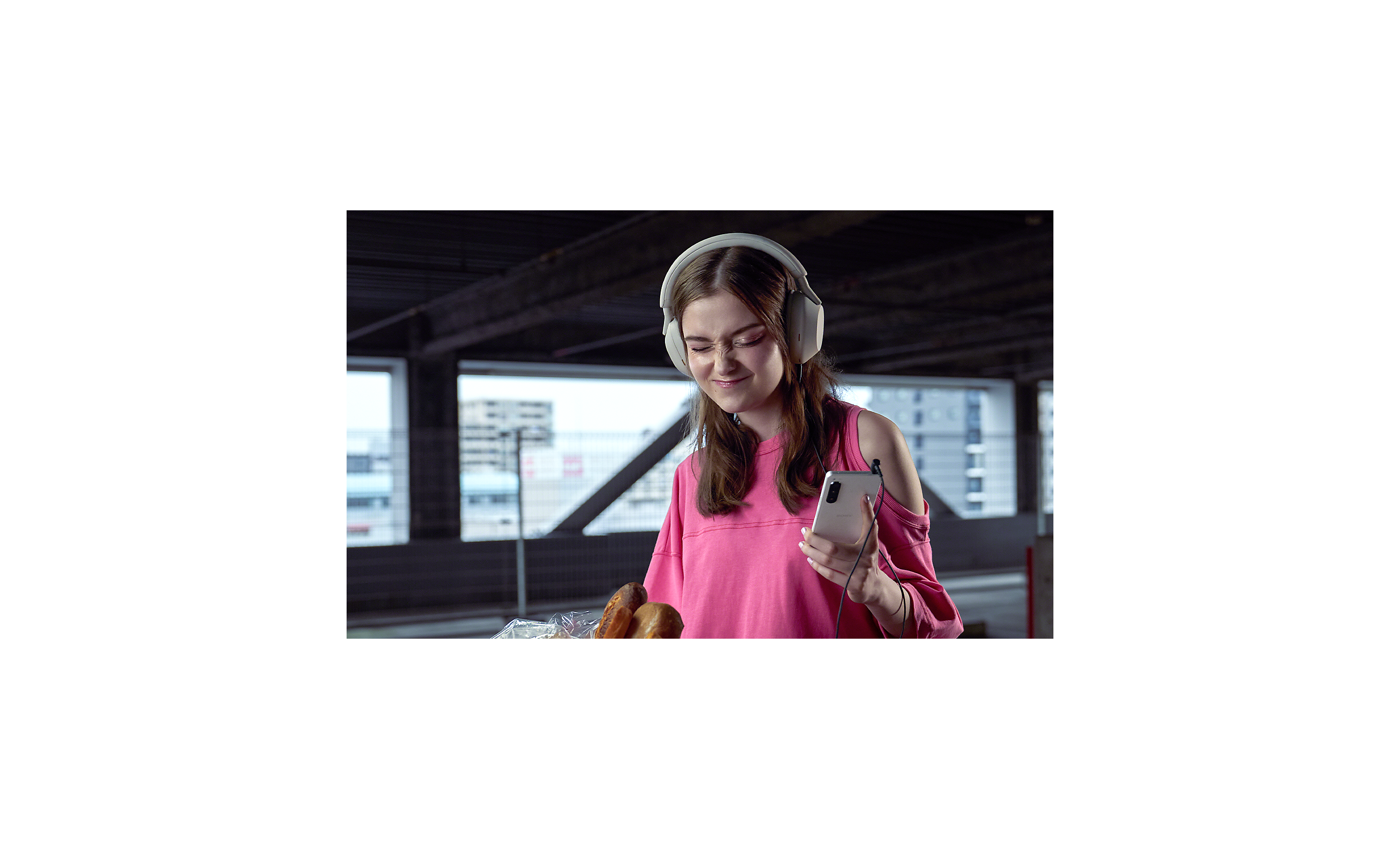 A woman wearing headphones, listening to music on her Xperia 5 IV