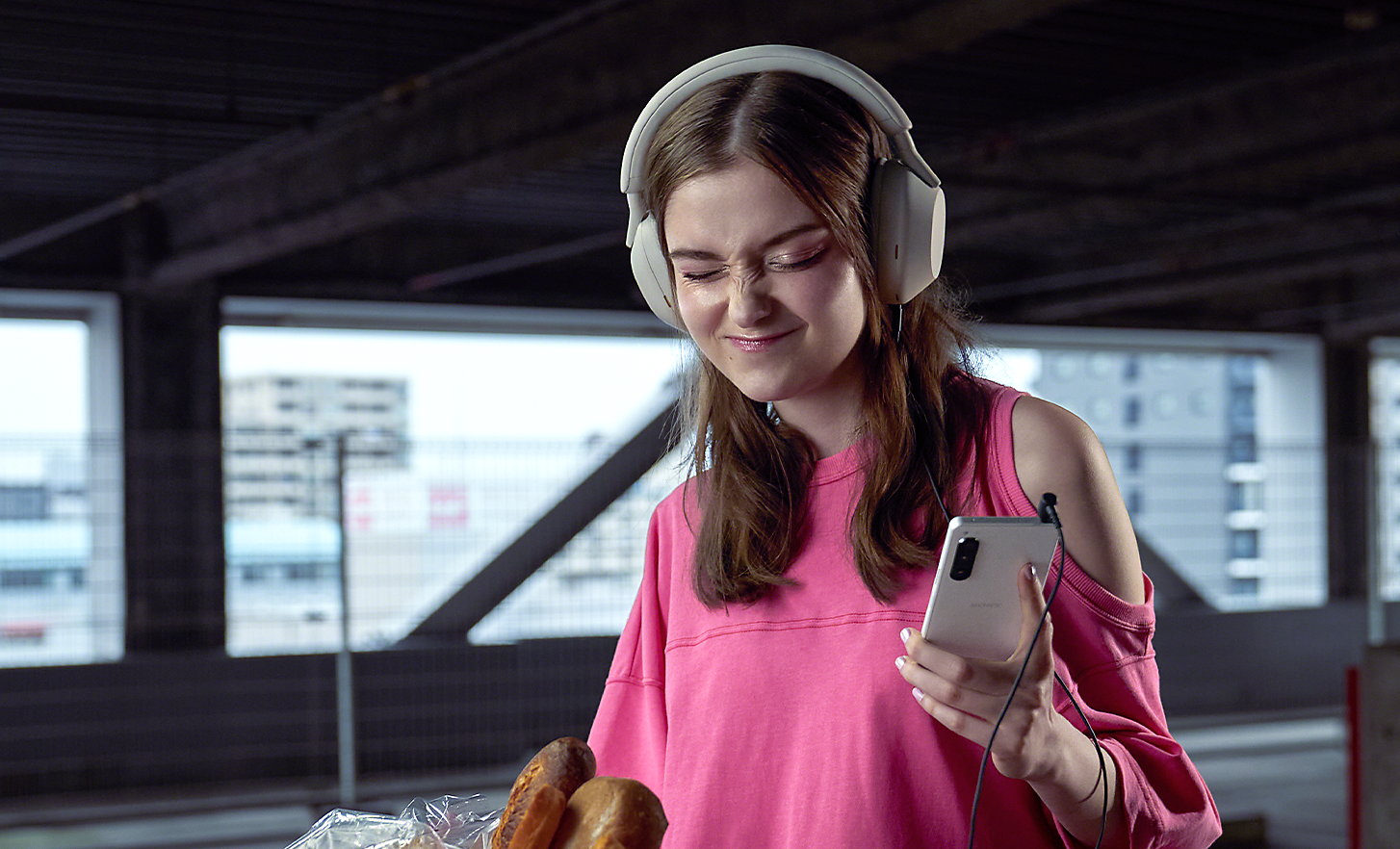 A woman wearing headphones, listening to music on her Xperia 5 IV