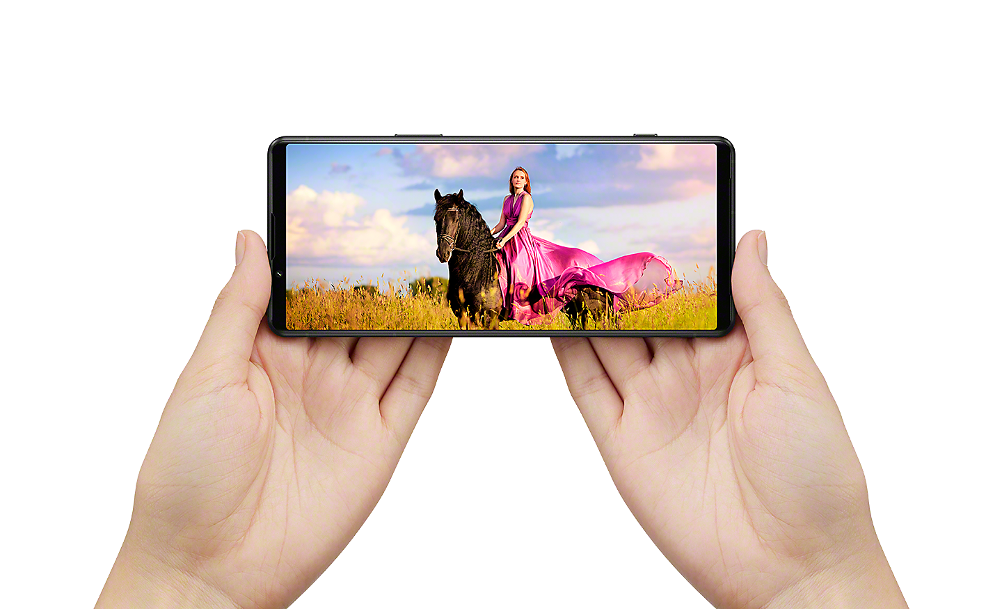 Mâini ținând un Xperia 5 IV în orientarea peisaj cu o imagine cinematică prezentând o femeie călare