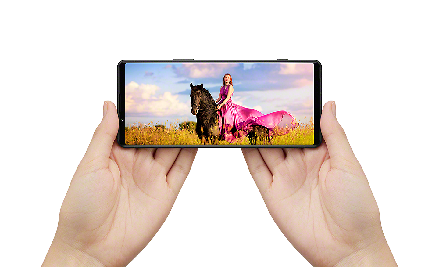 Mains tenant un Xperia 5 IV en mode paysage affichant la photo d'une femme à cheval en qualité cinéma
